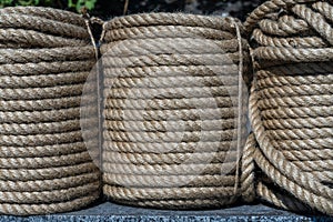 Natural jute hemp rope rolled into a coil, closeup. Brown spool of linen rope texture on the background