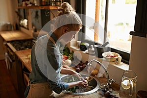 She a natural in the kitchen. a young woman washing vegetables in a rustic kitchen.