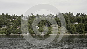 Natural landscape with rippling river and houses by the coast. Action. Countryside region, view from the river on a photo