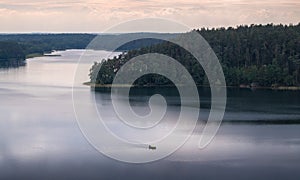 Natural landscape view from above the lake and trees with the sailing boat, reflections on the water and dramatic sky