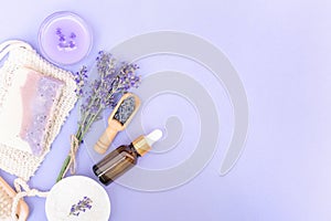 Natural lavender beaty self-care products for body and skin care over purple background with copy space