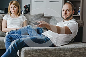 Natural, lifestyle image of attractive couple sitting on couch and preparing to watch a movie.