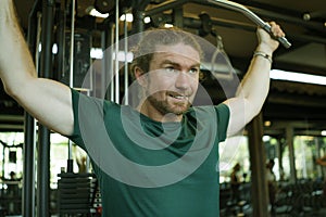 Natural lifestyle portrait of young athletic and attractive man training and body building doing muscular exercise with gym