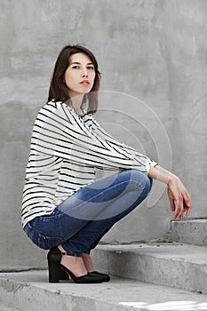 Natural light outdoors portrait of young fashionable brunette woman practicing model posing outdoors against urban style backgroun