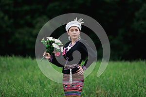 natural light portrait of asian young woman standing on green grass wearing traditional thai culture lanna dress style and flowers