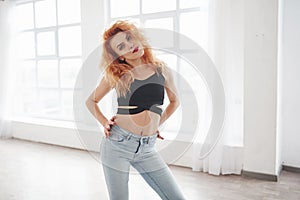 Natural lighting. Attractive redhead woman posing in the spacey room near the window