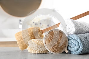 Natural loofah sponges and towels on table in bathroom