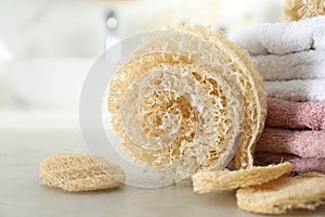 Natural loofah sponges and towels on table in bathroom, closeup