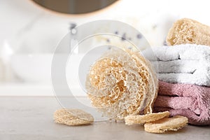 Natural loofah sponges and towels on table in bathroom, closeup. Space for text