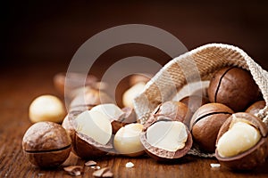 Natural macadamia nuts in canvas bag on wooden table.