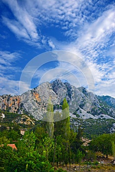 A natural-man-made landscape with a three-headed peak, a forest and an electric transmission line.