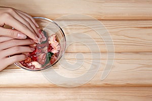 Natural Manicure, Hand Care. Soaking Finger Nails in Bath with Herbal Oil and Floral on White Wooden Table. Copy Space