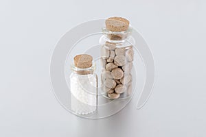Natural medicine bottles with herbal pills and globules on gray background