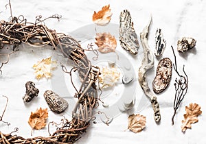 Natural nature objects for creative crafts - vine wreath, stones, leaves, wood on a light background, top view.