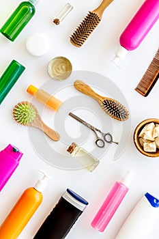 Natural oil for hair near scissors, shampoo bottle, and brush on white background top view pattern