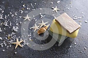 Natural organic bars of soap on the wet dark surface, sea salt and shells