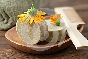 Natural organic calendula solid shampoo pieces, calendula flowers, wooden hair comb and towel.