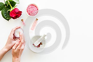 Natural organic cosmetics in hands with rose extract on white background top view copyspace