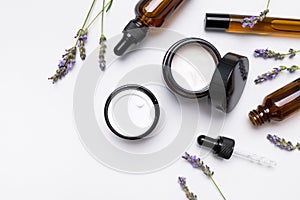 Natural organic cosmetics with lavender extract on white background flat lay top view. Glass bottles with pipette, jars of face