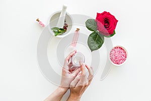 Natural organic cosmetics with rose extract in hands on white background top view