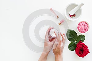Natural organic cosmetics with rose extract in hands on white background top view copyspace