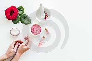 Natural organic cosmetics with rose extract in hands on white background top view copyspace