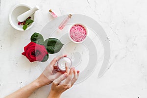 Natural organic cosmetics with rose extract in hands on white marble background top view copyspace