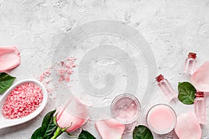 Natural organic cosmetics with rose oil. Cream, lotion, spa salt on grey background top view copyspace