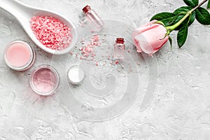 Natural organic cosmetics with rose oil. Cream, lotion, spa salt on grey background top view copyspace