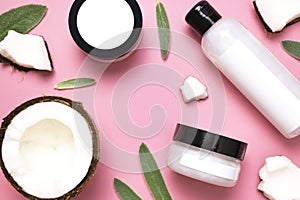 Natural organic eco cosmetics with coconut oil. Cosmetic containers with cream and lotion, broken coconut, green leaves on pink