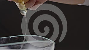 Natural organic egg falling into a glass bowl on a flour background. Preparing ingredients for homemade baking. Slow