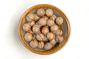 Natural organic macadamia nuts in wooden bowl on gray concrete background Flat lay Top view Healthy snack Nuts with essential oil