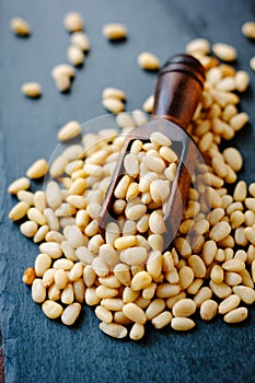 Natural organic pine nuts on a black slate with scoop.