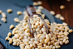 Natural organic pine nuts on a black slate with scoop.