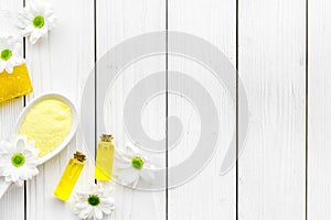 Natural organic spa cosmetics for skin care with chamomile. Spa salt, oil, soap on white wooden background top view copy