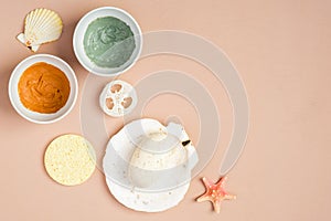 Natural organic SPA cosmetics. Top view facial clay masks, homemade soap, loofah, sponge on peach background. Face skin care and