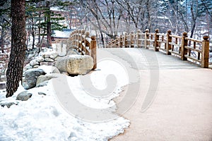 natural park covered by snowy yard and the stone bridge in winter season background is high pines mountain