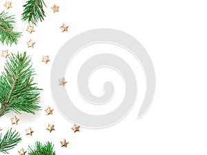 Natural pine branches are on a white background and are decorated with golden stars. Christmas, New Year concept in a minimalist