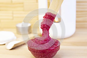 Natural pink body scrub made from sugar. Pink scrub in a glass cup on a background