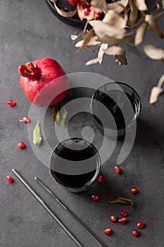 Natural pomegranate juice in a glasses on a dark background with fresh fruit and bouquet