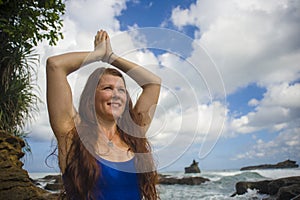 Natural portrait of young attractive and happy red hair woman practicing meditation and relaxation yoga lotus exercise sitting at
