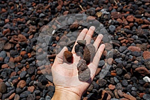 Natural pumice stone or of volcanic rocks in hand on Perissa beach, Santorini, Greece