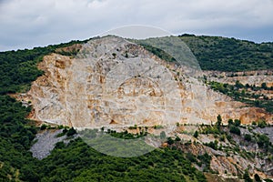 Natural quarry is located near road against backdrop of Rhodope Mountains and hills with forests and mountain vegetation