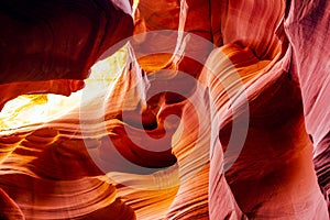 Natural red-orange sandstones stacked in layered fire waves in a narrow sandy labyrinth in Lower Antelope Canyon in Page Arizona