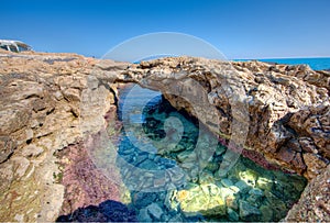 Natural rock arch over a tidal pool at the seaside