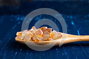 Natural rock sugar in wooden spoon on rustic table