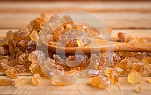 Natural rock sugar in wooden spoon on rustic table