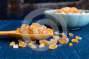 Natural rock sugar in wooden spoon on rustic table