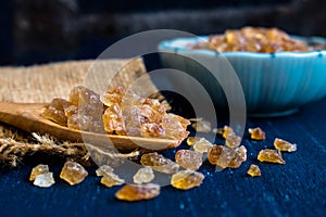 Natural rock sugar in wooden spoon on rustic table