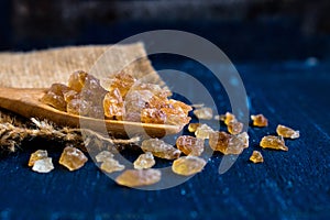 Natural rock sugar in wooden spoon on rustic table